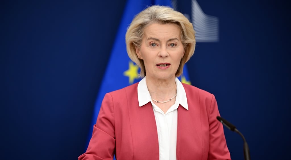ursula von der leyen, pink suit, white collar shirt, blonde woman, EU flag