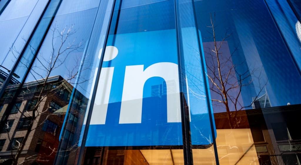 LinkedIn logo behind glass wall of a huge building, reflection of the cityscape