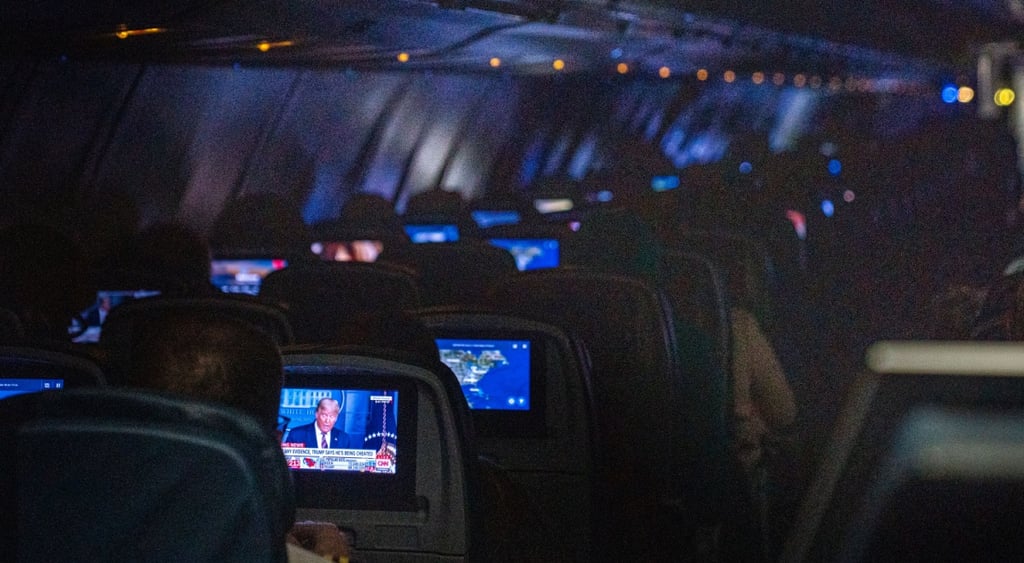 dark plane cabin, little shiny monitors, donald trump on cnn, blue screen