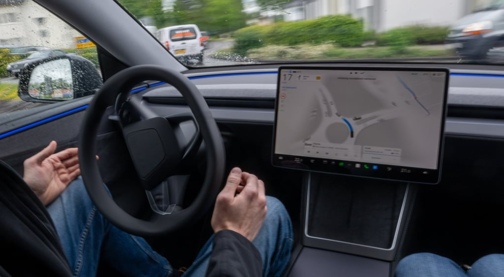 self driving lest, white male hands off wheel, big creen, black wheel, blue jeans, road ahead