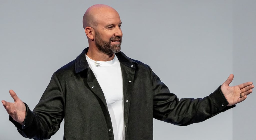 Andrew Bosworth, white bald man, white shirt, black jacket, arms spread and up, dark beard