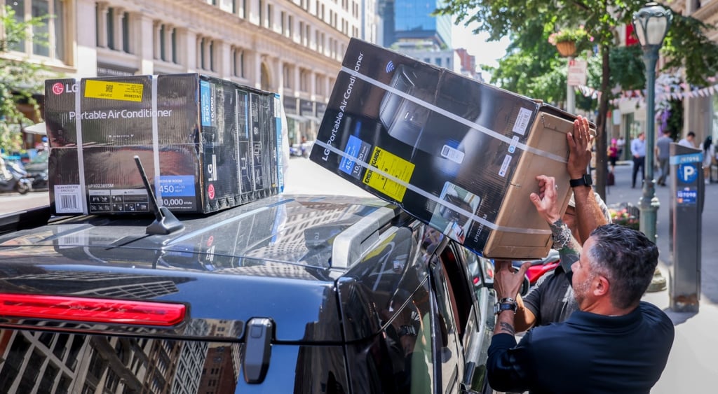 white male, black box with air conditioner, car rooftop blue bus on new york street, sunny day, black t-shirt, green tree