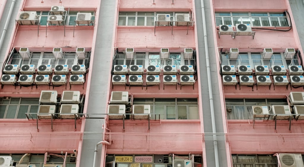 light pink building, five rows of white air conditioners, white frame windows