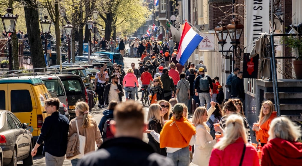 sunny day in amsterdam, dutch flag, long grey hair, pink jacket, green trees, early spring, brown jacket, yellow car