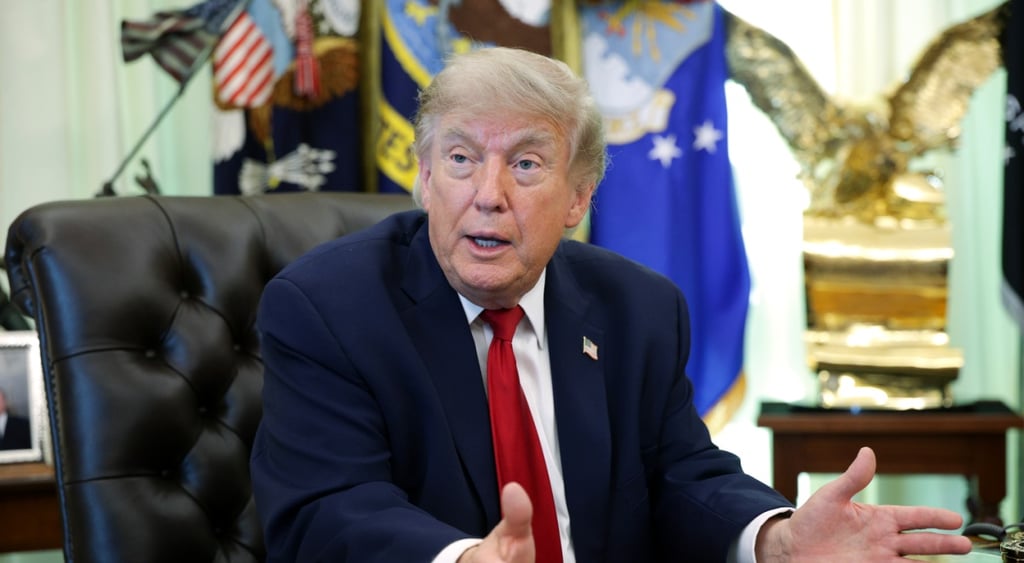 donald trump, dark suit, white collar shirt, dark red tie, usa flag pin, black leather chair