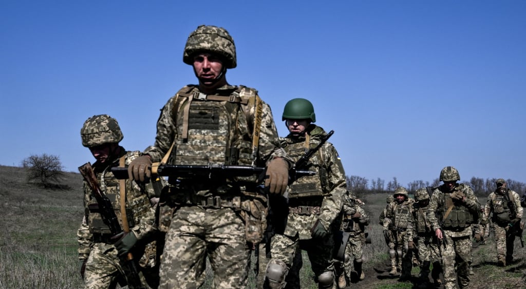ukraine armed forces, nine men in field, uniform, helmets, clear blue sky, black shotguns