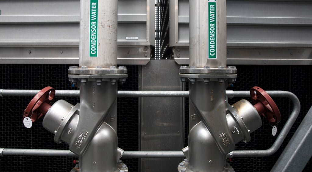 two grey pipe, green condensed water stickers on them, red round handles on both