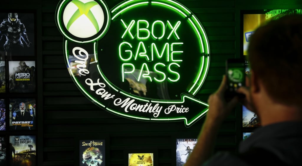 xbox game pass signage, green lit in dark room, white male takes picture of it
