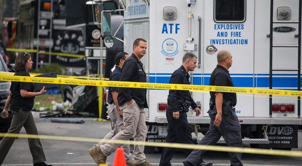 ATF investigators at the scene of investigation. 3 agents walk in front of ATF van with logo.
