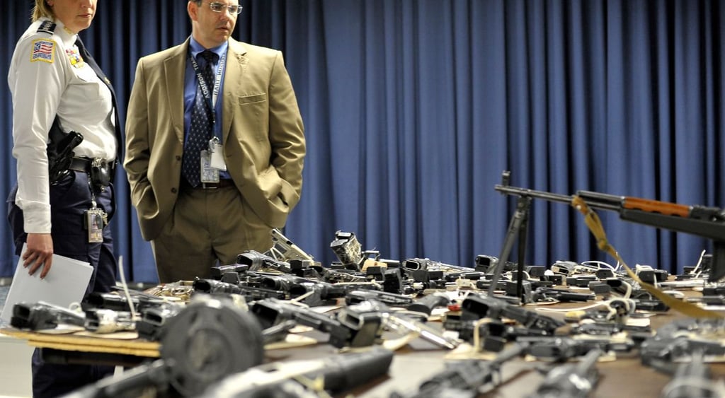 local police ATF agent at table full of confiscated guns