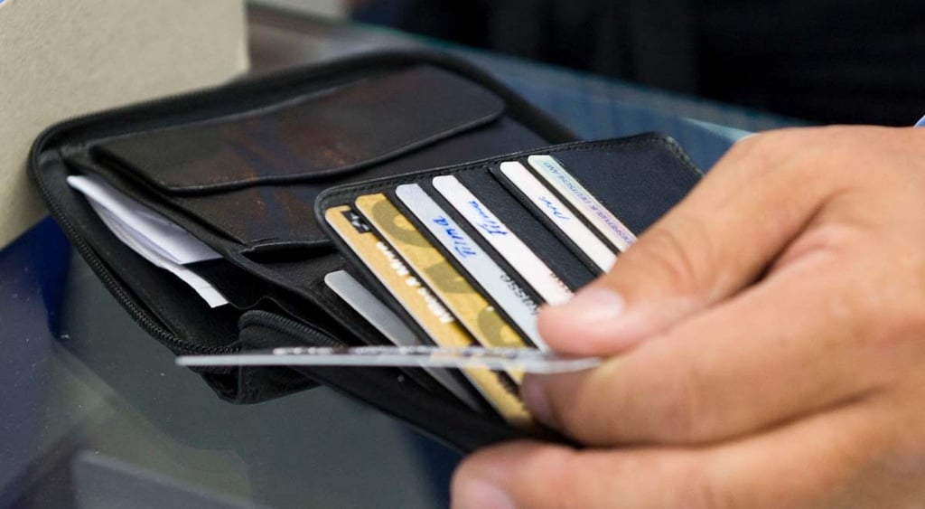 An individual's hand picking out a credit card out of their wallet