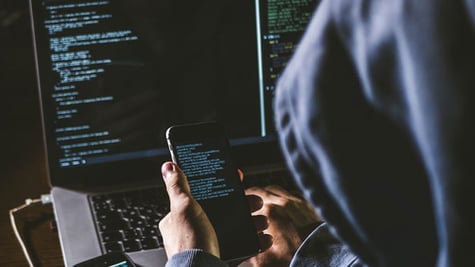 Anonymous person in the hood sitting in front of computer