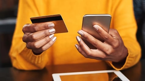 woman holding credit card and smartphone