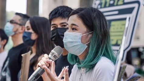 A girl with a facemask speaking into a microphone