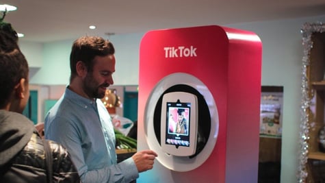 A man in from of TikTok screen and logo
