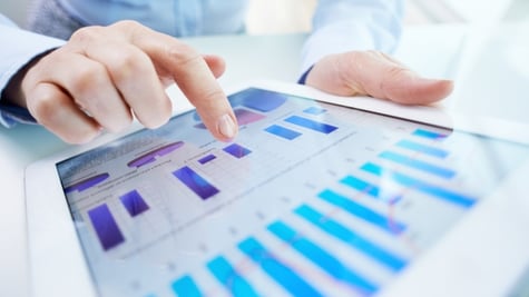 Human hand pointing at touchscreen with business document with graphs