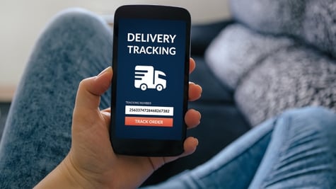 man holding a phone with delivery message on the screen