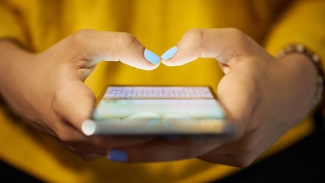 Young woman using cell phone to send text message on social network