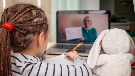 Girl studying and looking at teacher on laptop screen