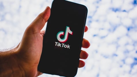 Hand holding mobile phone with TikTok app logo