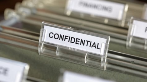 Inside of a filing cabinet with green folders and focus on confidential label
