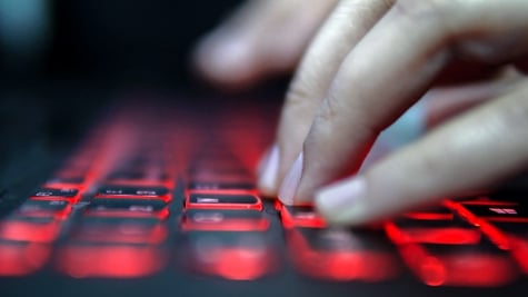 Teenage Hacker Girl Attacks Corporate Servers in Dark, Typing on Red Lit Laptop Keyboard. Room is Da