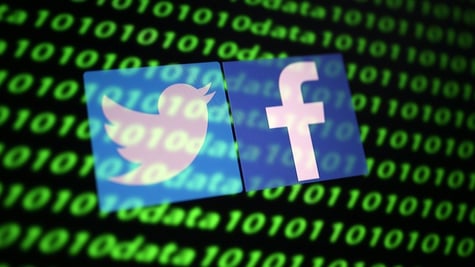 The Twitter and Facebook logo along with binary cyber codes are seen in this illustration