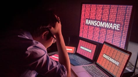 Young Asian male frustrated, confused and headache by ransomware attack on desktop screen, notebook 