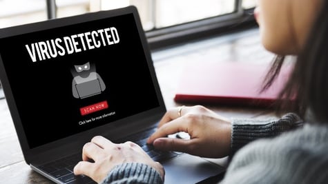 Woman looking at computer screen with inscription Virus Detected