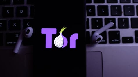 Tor on mobile phone placed on laptop keyboard near headphones