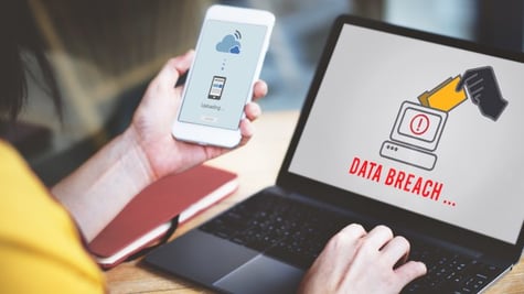 Person using laptop with Data breach inscription on screen with one hand and uploading on mobile on 