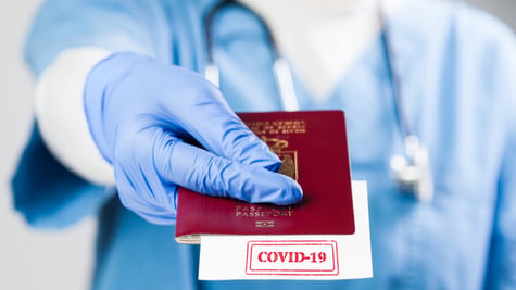 Doctor holding passport with COVID-19 sign stamped onto white paper
