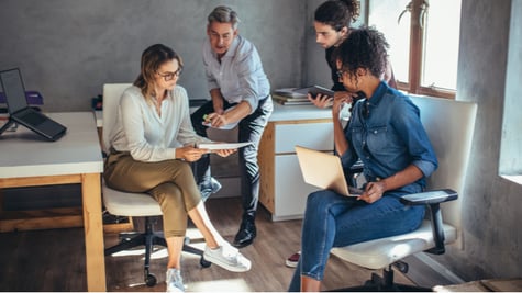 Diverse group of business people working together at a small office discussing a new business plan