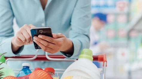 woman with cart looking at mobile