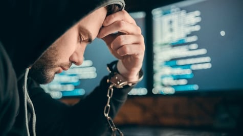 Arrested hacker criminal in handcuffs