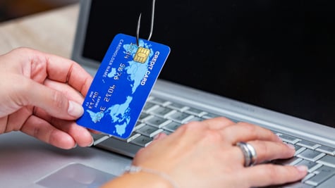 Phishing scam with credit card in fishing hook. Woman typing her credit card information on scam sit