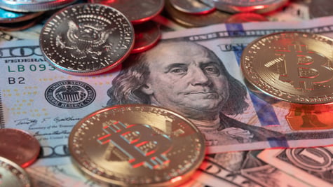 Bitcoin Coins on top of US Dollar Banknotes and Dollar coins in the background