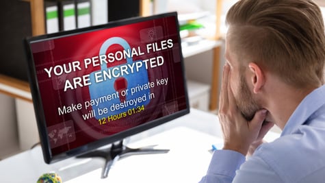Worried Businessman Looking At Computer With Ransomware Word On The Screen At The Workplace