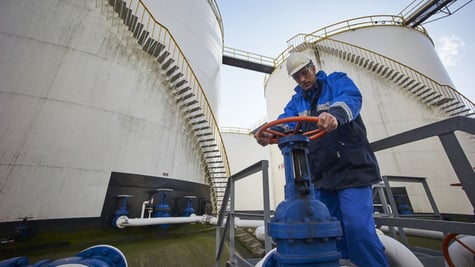 man working with large white fuel containers against blue sky