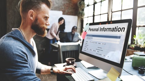 Young man looking at PC screen with Personal Information inscription