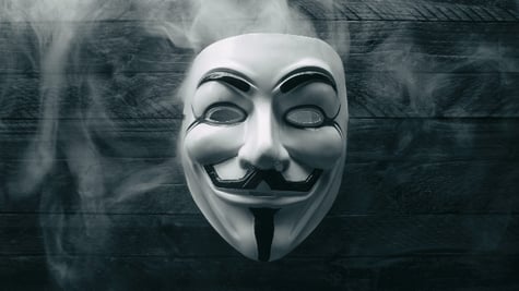Studio shot of a Anonymous Vendetta mask with smoke on wood