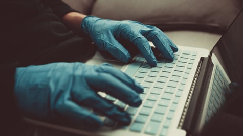 Person with gloves typing keyboard