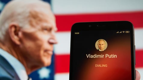 Smartphone with Vladimir Putin contact seen on it's screen and Joe Biden seen on the background.
