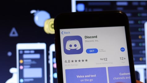 Discord icon on phone screen with logo on blurry background