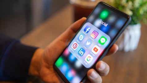 Man holding mobile with icons of social media on the screen