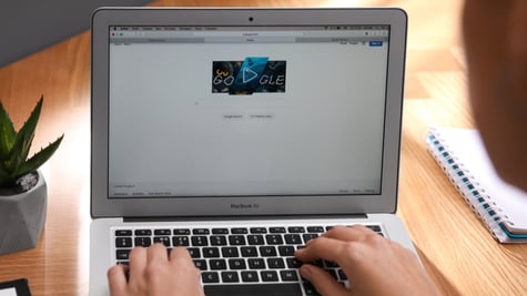 Person using Google search engine on MacBook Air laptop