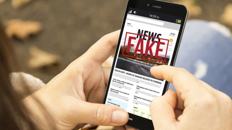 young woman with smartphone reading fake news at the park
