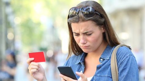 Worried girl having problem paying online with credit card and smart phone in the street