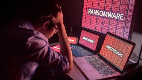 Young Asian male frustrated, confused and headache by ransomware attack on desktop screen