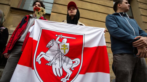 Protesters near the embassy of Belarus holding white-red-white flag of Belarus